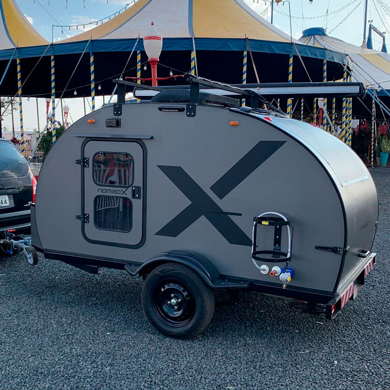 Mini trailer NomadX visto lateralmente, com grande “X” na lateral e rack com toldo superior.