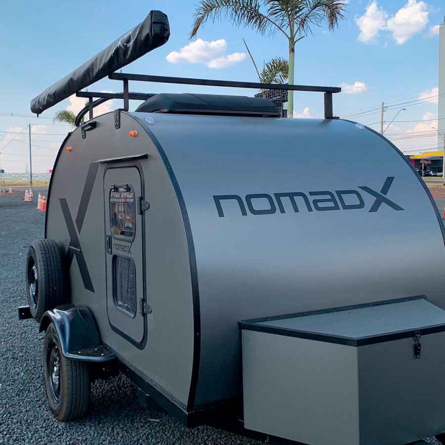 Mini trailer NomadX cinza visto de frente e lateral, com rack superior e design compacto.